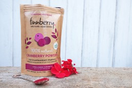 A photo of the finnberry cranberry pack, next to spoon and flowers