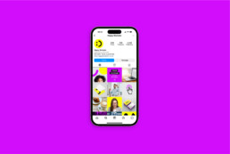 An iPhone showing the Happy Marketer Instagram grid, on a purple background created by branding agency DBC Creative Agency